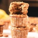 almond banana muffins stacked with a bite out of the top one.