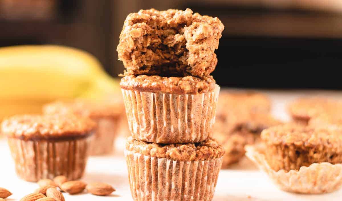 almond banana muffins stacked with a bite out of the top one.