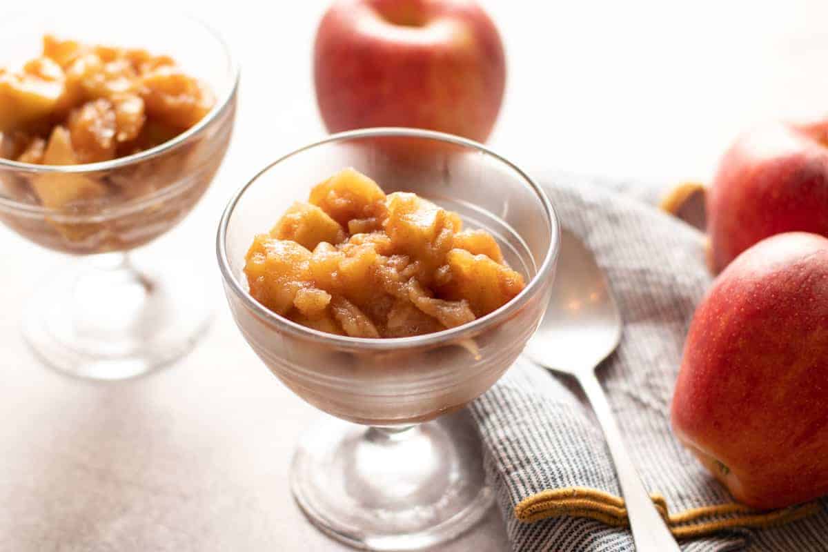 Cinnamon Maple Chunky Applesauce. in clear bowl with apple to the right.