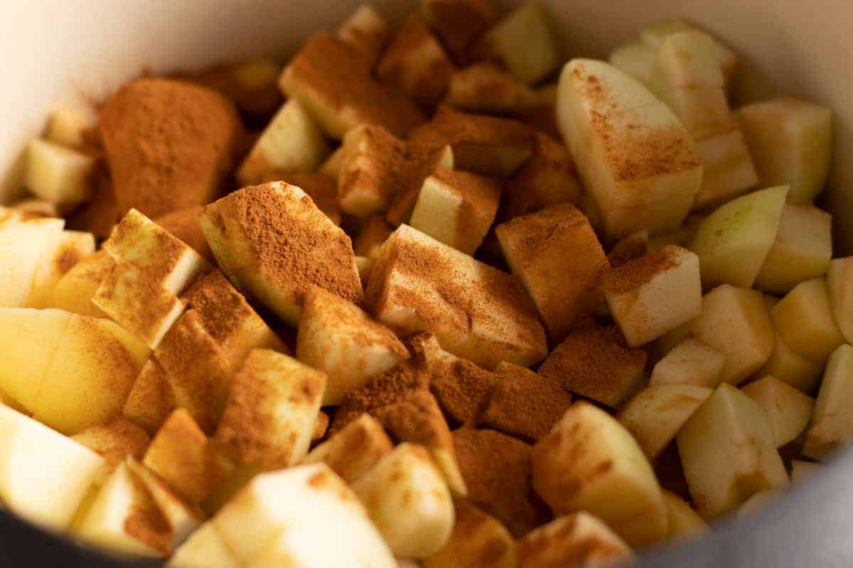 chopped apples in dutch oven covered with cinnamon