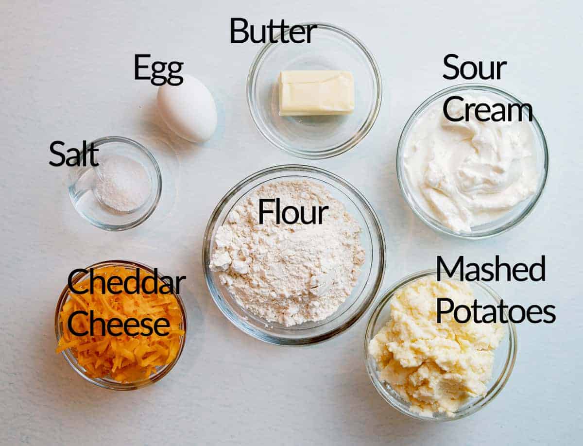 picture of ingredients for recipe including salt, egg, butter, sour cream, cheddar cheese, flour and mashed potato. 