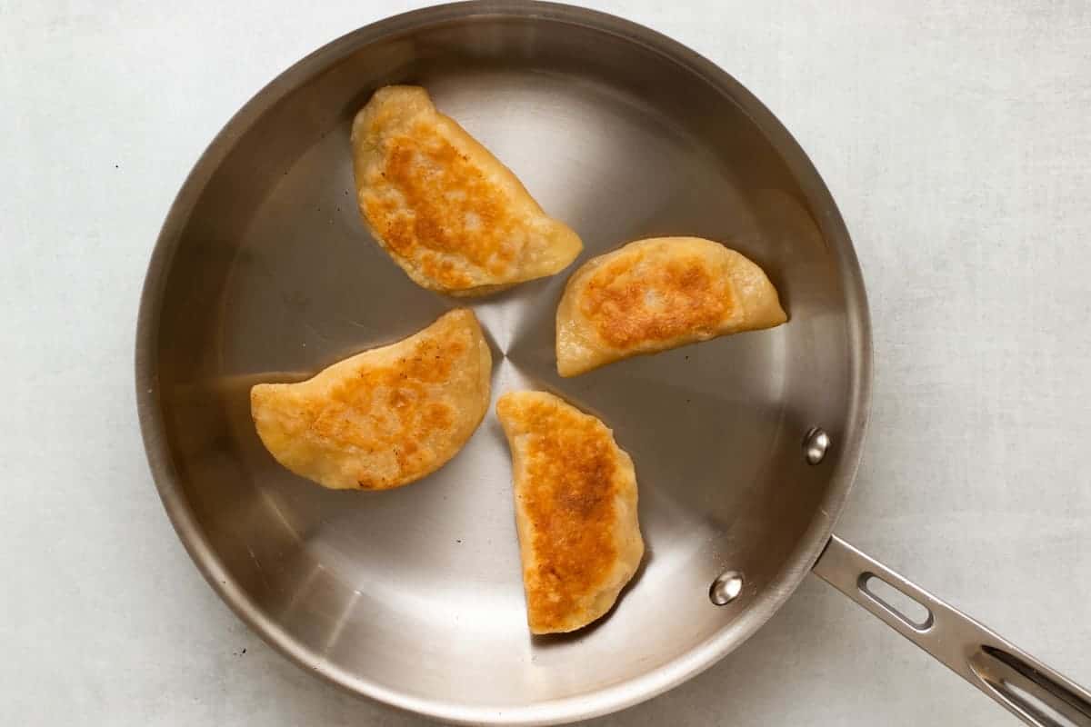 finished browned pierogi sitting in stainless steel pan