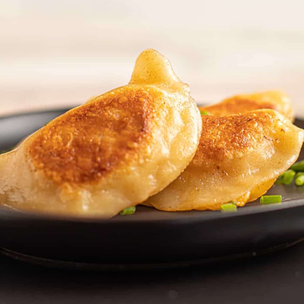 two finished pierogies on black plate