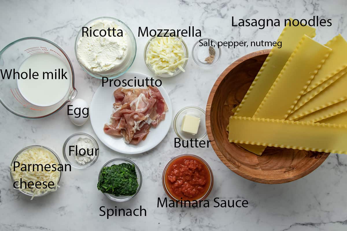 ingredients picture for the lasagna rolls with spinach. Whole milk, ricotta, mozzarella, lasagna noodles, salt, pepper, nutmeg, prosciutto, egg, flour, spinach, and butter.