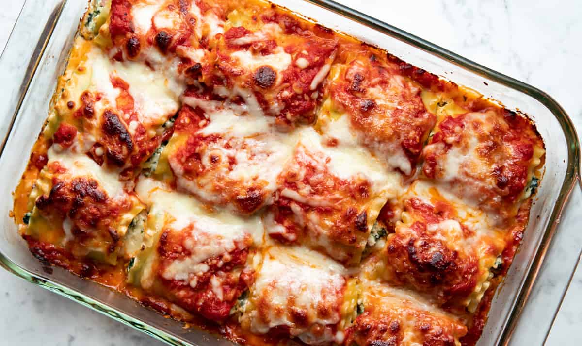Lasagna rolls fully baked out of the oven in glass dish.