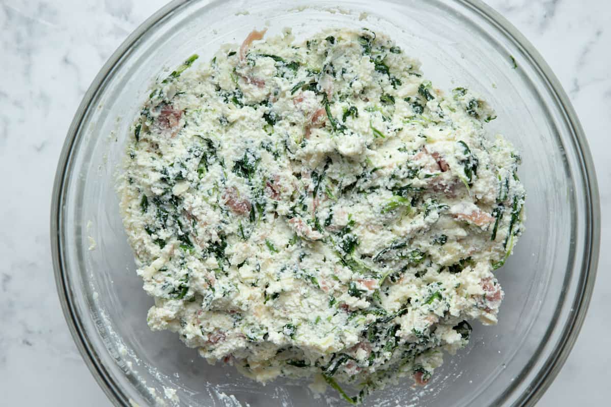mixture of ricotta, spinach, egg, parmesan cheese, prosciutto, and seasonings in a glass bowl.