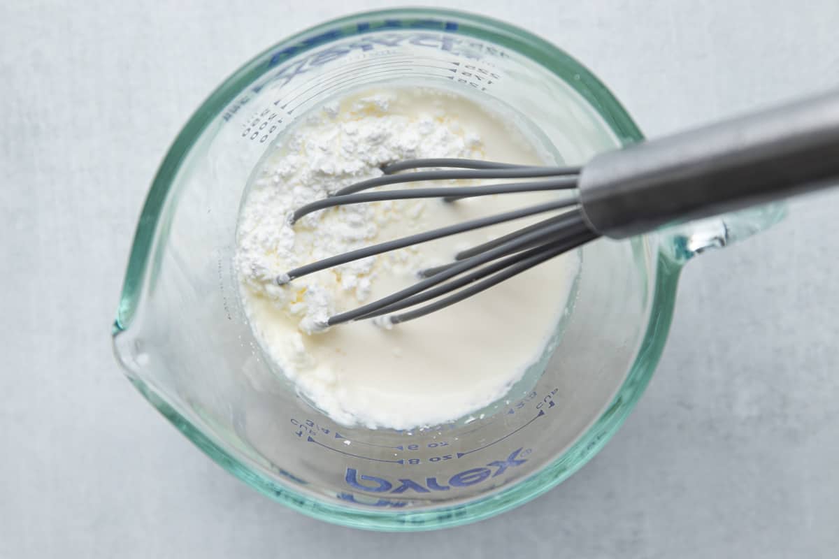 a liquid measuring cup with milk and cornstarch 