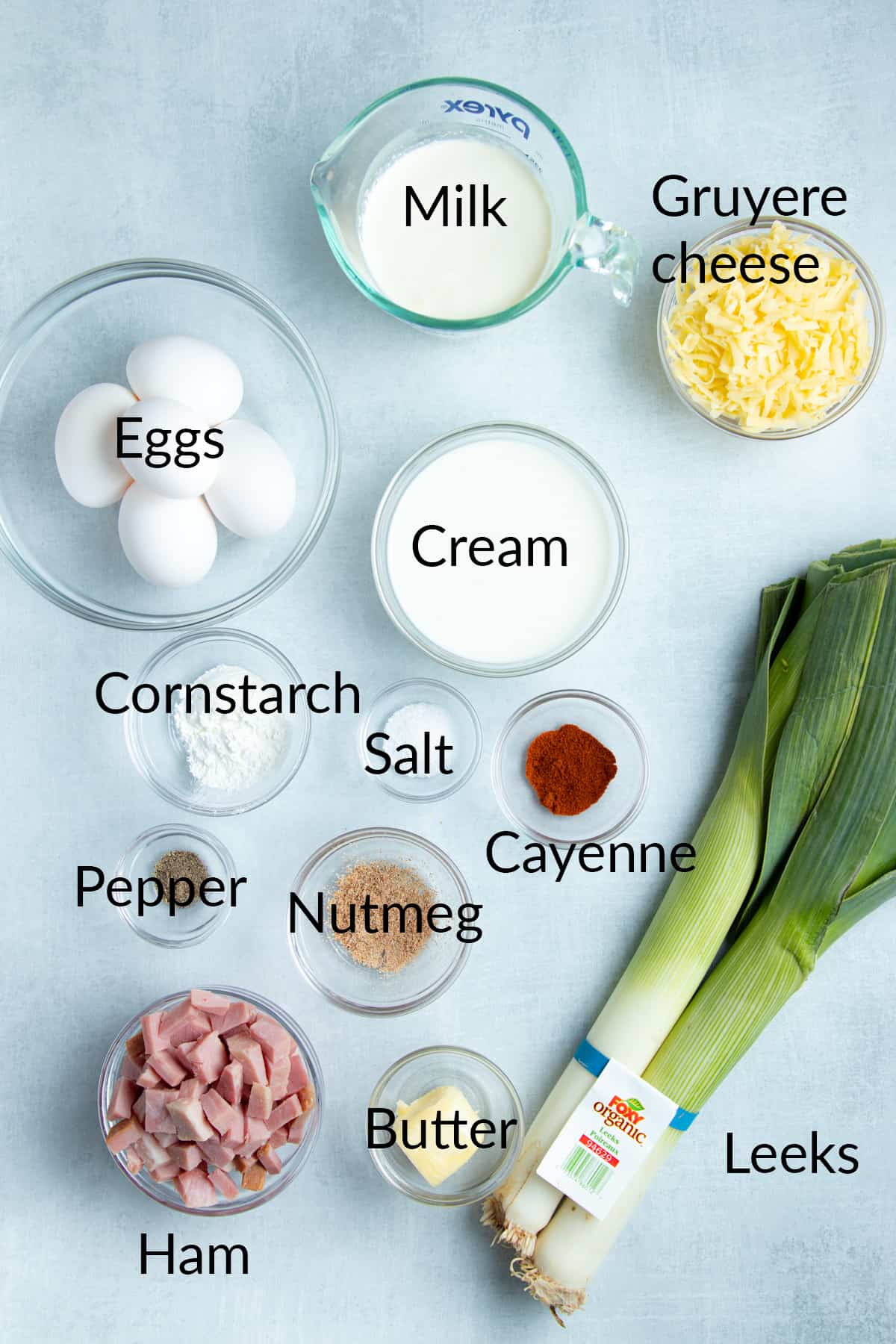 picture of ingredients, milk, eggs gruyere cheese, cream, cornstarch, salt cayenne, pepper, nutmeg, ham, butter, leeks 