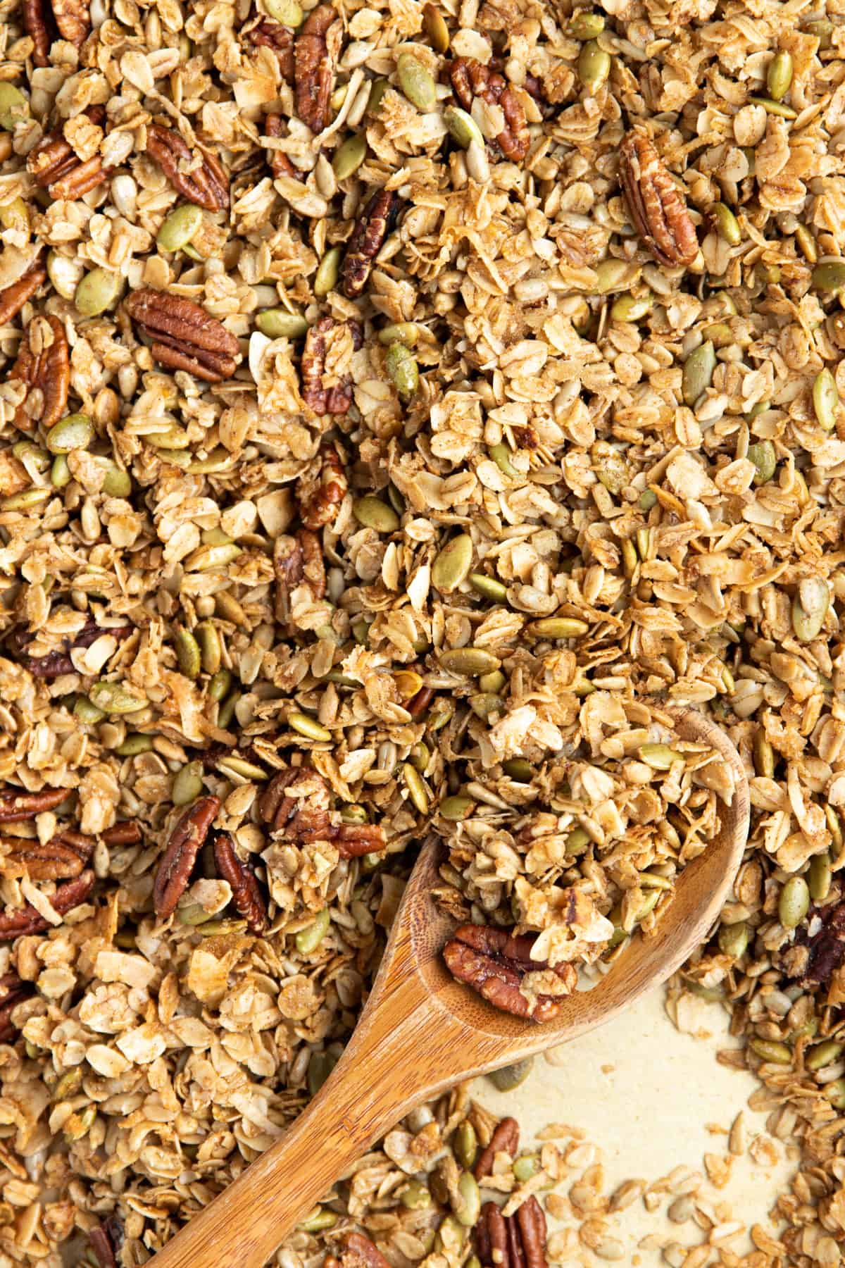 granola on a sheet pan with wooden spoon