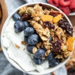 white bowl of yogurt with blueberries and granola on top