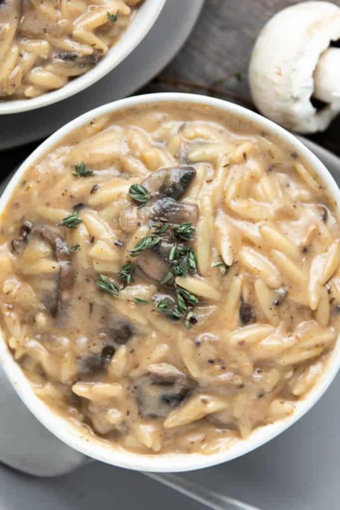 creamy mushroom orzo soup in a white bowl on a grey plate