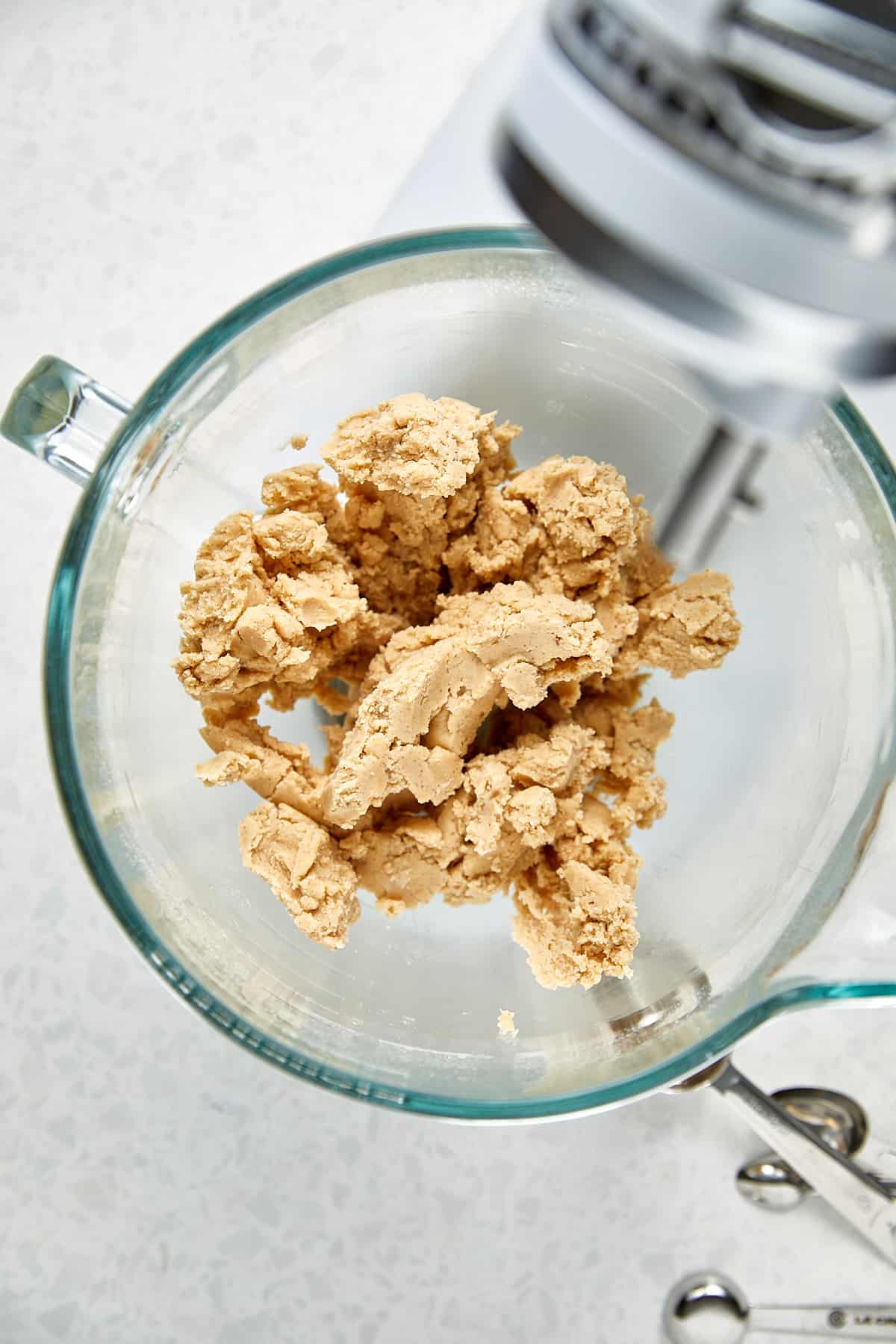 fully mixed butter and flour dough in a clear bowl sitting on a kitchen aid mixer.