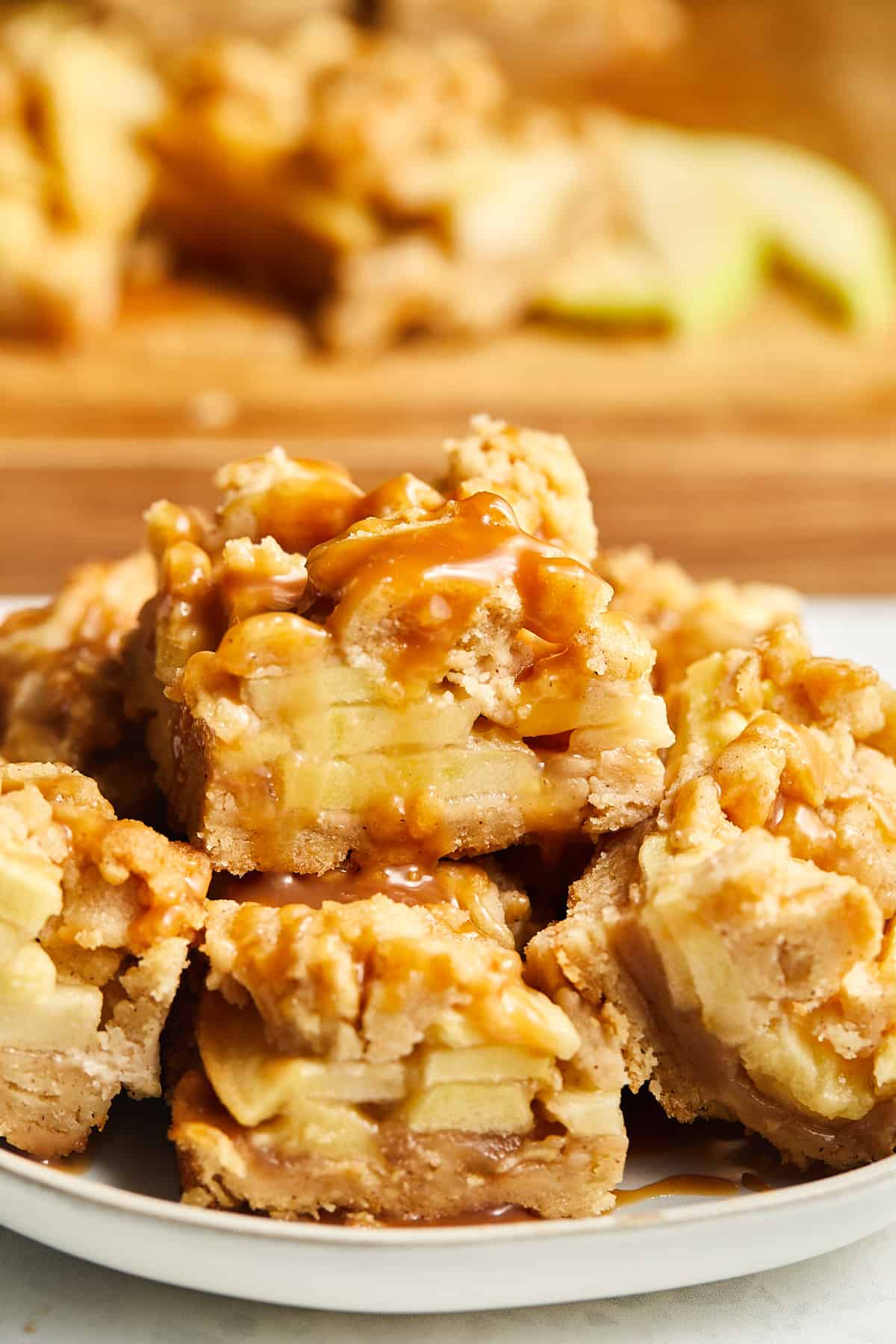 Salted Caramel Apple Pie Bars stacked with a cutting board in background. 