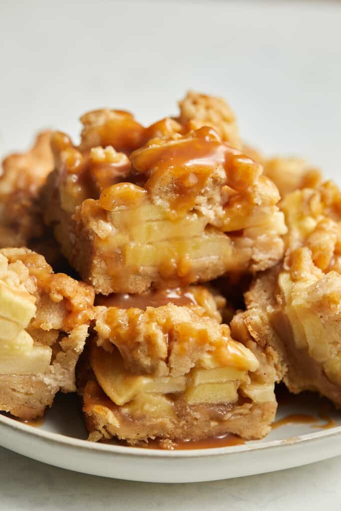 Salted caramel Apple pie bars stacked on white plate.