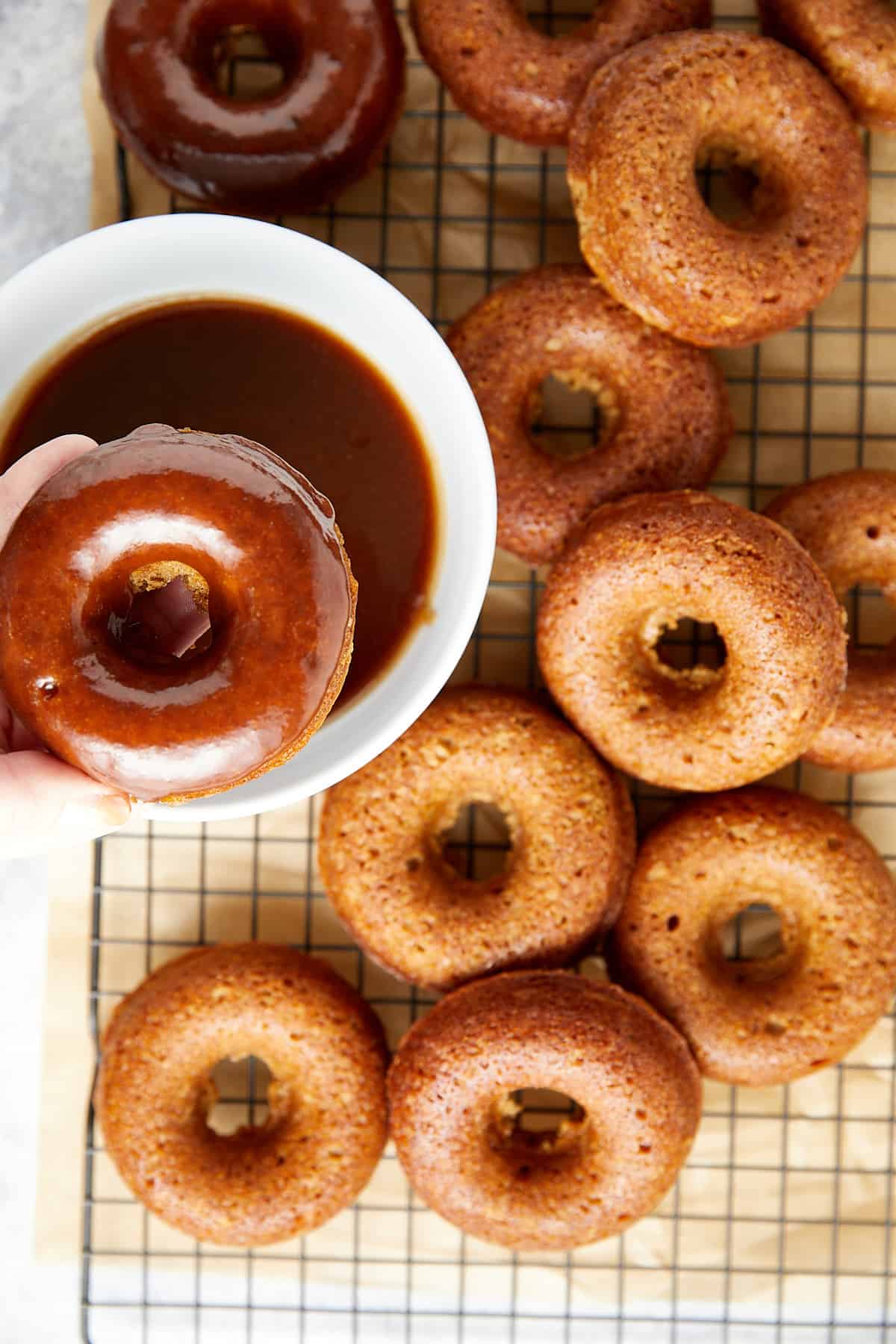 baked donuts on wire rack with glaze in a white bowl. 