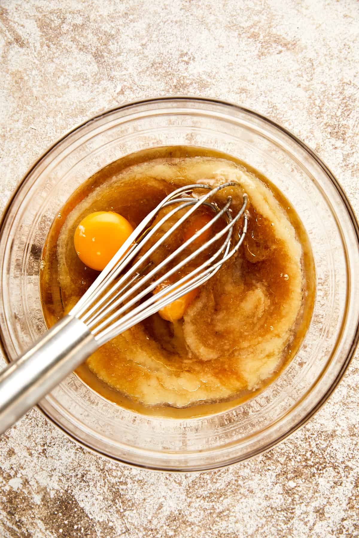 eggs, unsweetened applesauce, maple syrup, oil and vanilla in a clear bowl.
