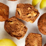 healthy apple muffins split in half with whole muffins with apple slices and whole apple.