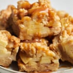 Salted apple pie bars stacked on white plate.