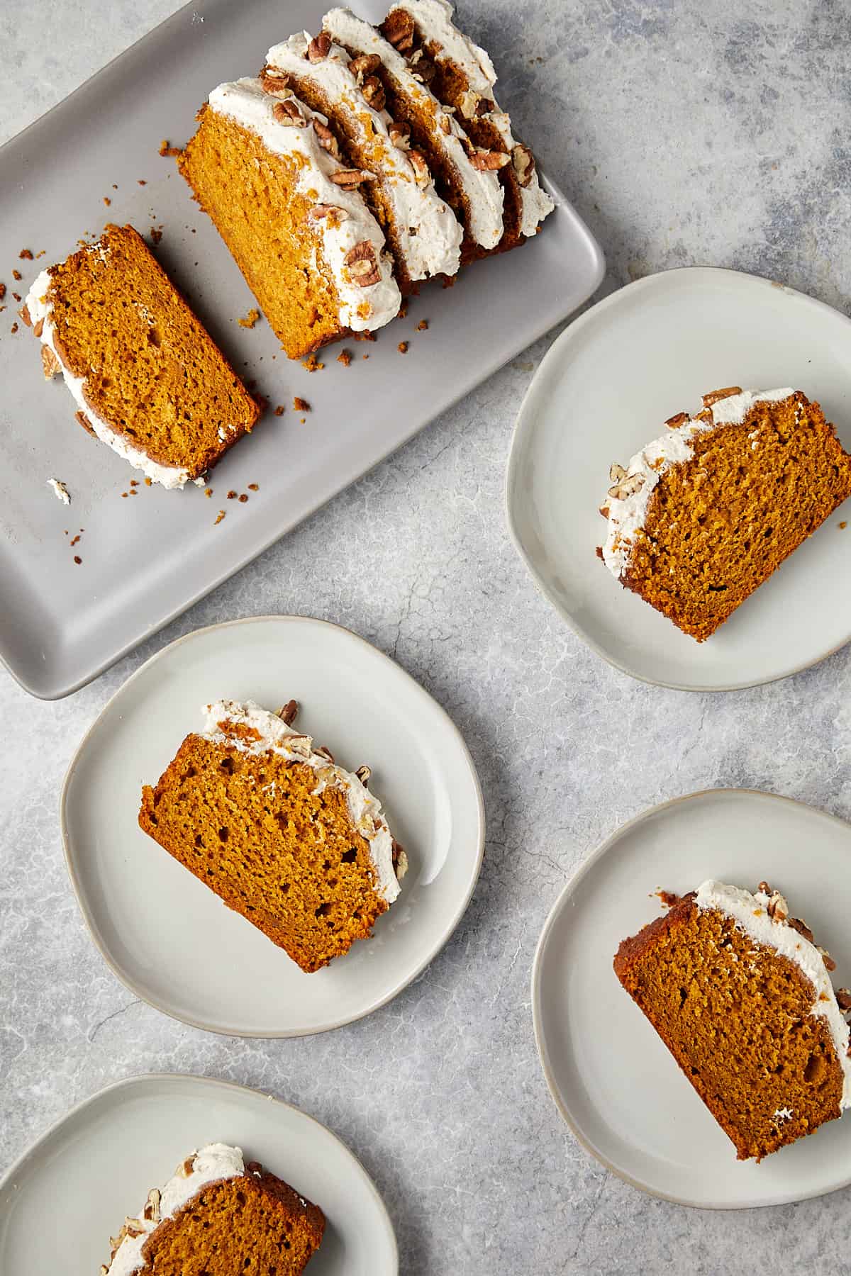 pumpkin bread with cream cheese topped with pecans sliced on white plates.