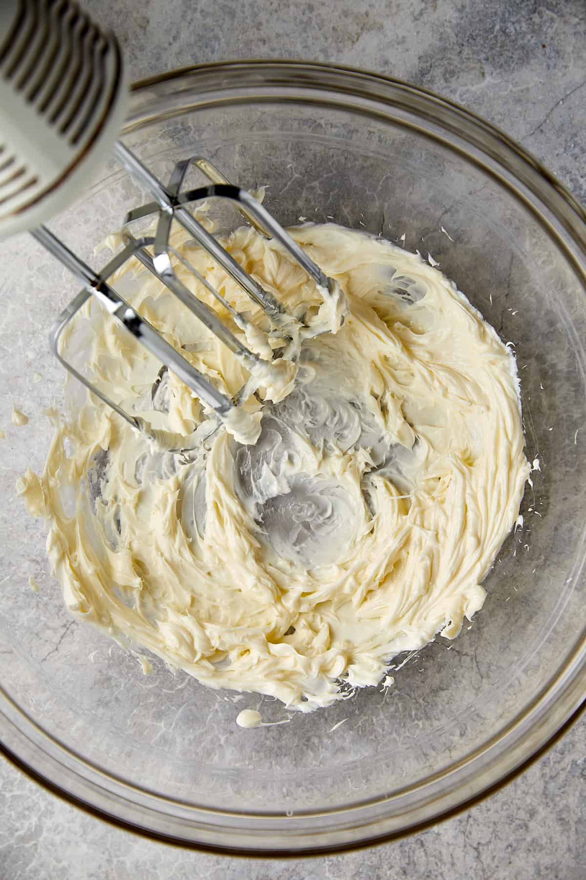 Butter and cream cheese mixed together with a handheld mixer.