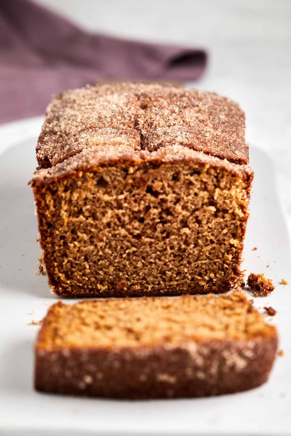 Looking straight at the apple cider loaf cake sliced with one slice laying in front.