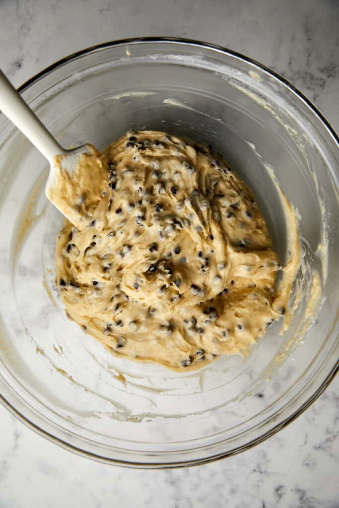 looking down at a glass bowl with wet and dry ingredients with chocolate chips mixed in.