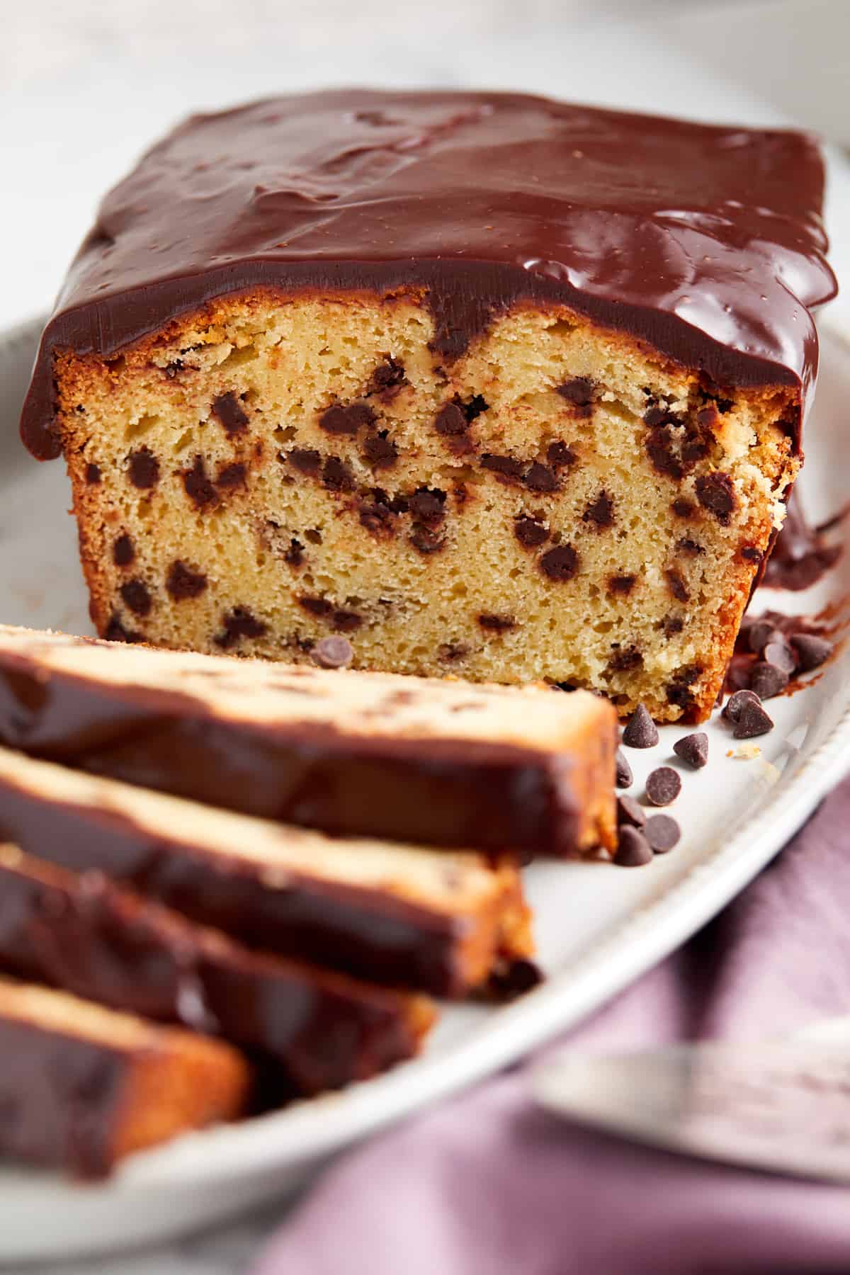 looking at baked and frosted chocolate loaf cake with slices in front of cake.