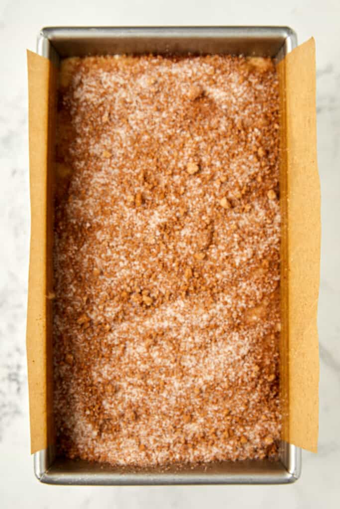 looking down at cinnamon crunch banana bread batter in a loaf pan with cinnamon sugar on the top.