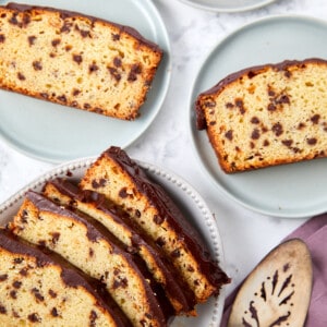 looking down at a baked chocolate loaf caked sliced on plates with a silver server utensil.