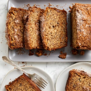 looking down cinnamon crunch banana bread sliced on grey platter and on plates with a fork.