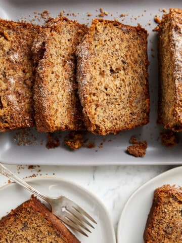 looking down cinnamon crunch banana bread sliced on grey platter and on plates with a fork.