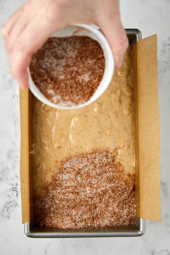 Looking down at banana bread batter with cinnamon sugar topping being poured on the top.