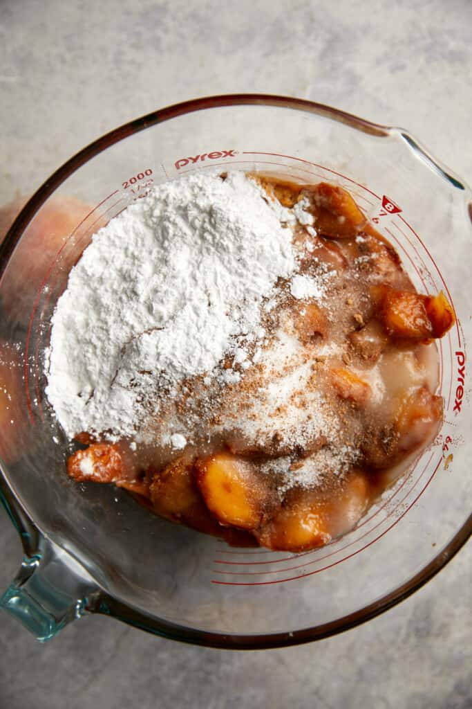 looking down at sliced peaches with tapicoa flour, sugar and spices laying on top