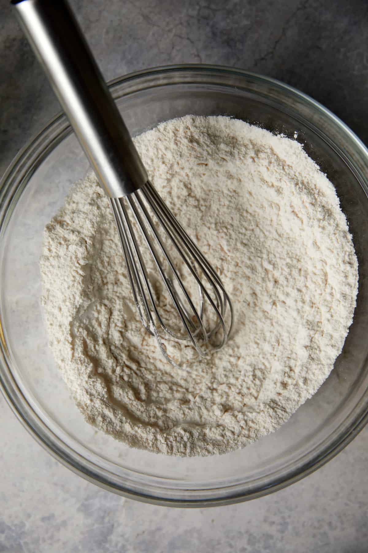 looking down at clear bowl with dry ingredients mixed with a whisk