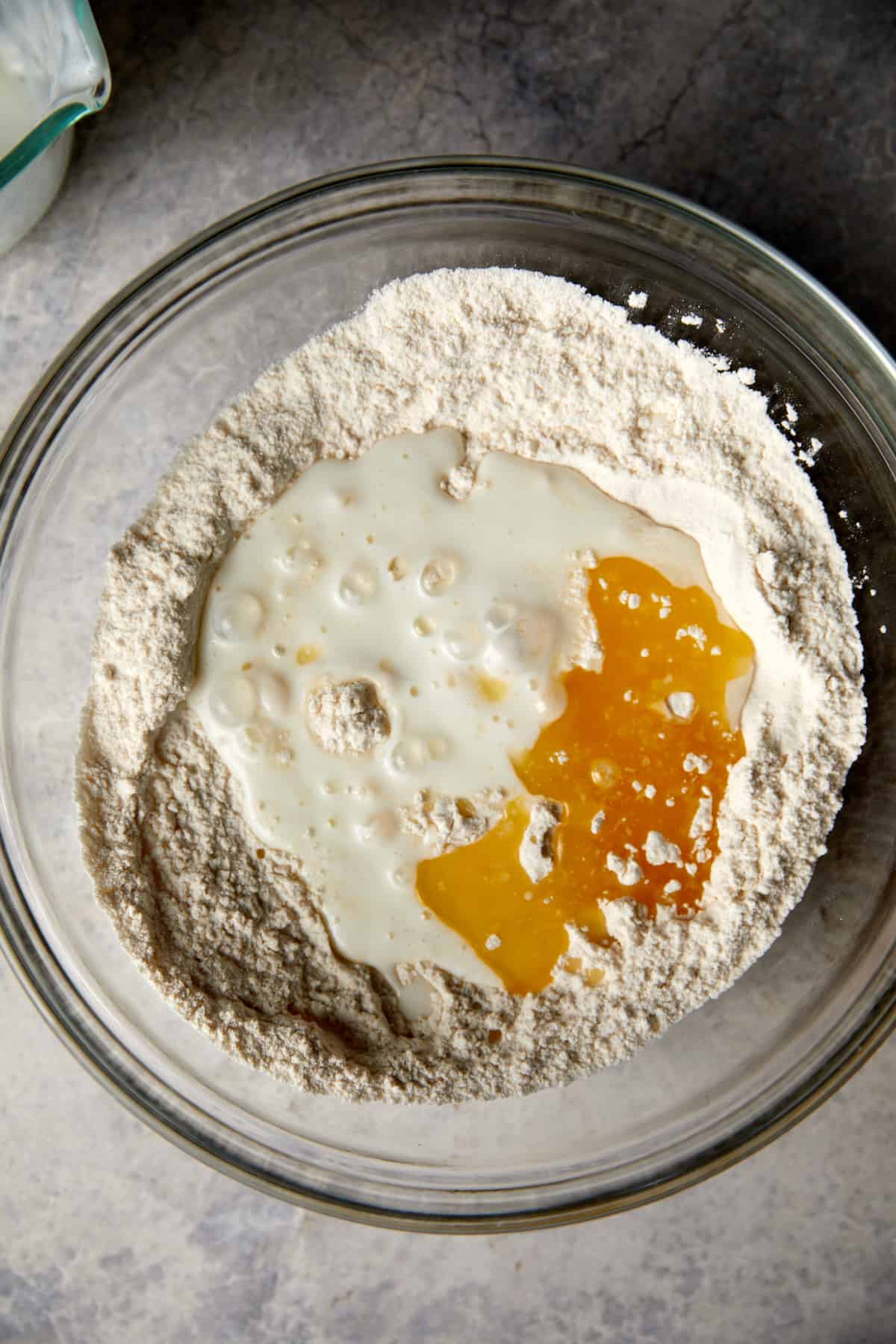 looking down at clear bowl with the milk and butter poured into flour for biscuit topping