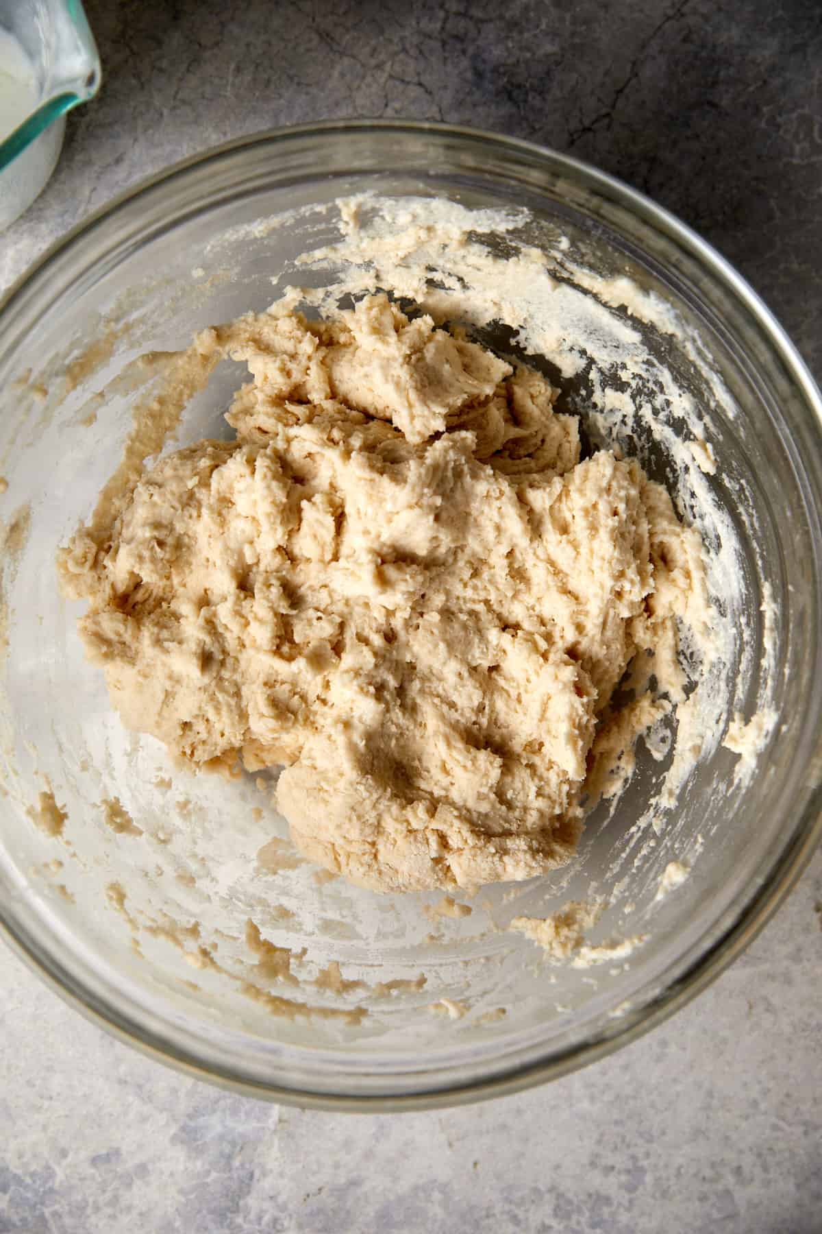 looking down at clear bowl with biscuit dough topping mixed together