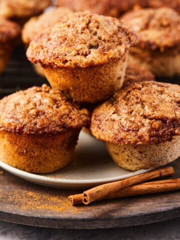 close up view of three cinnamon swirl muffins stacked on a white plate.