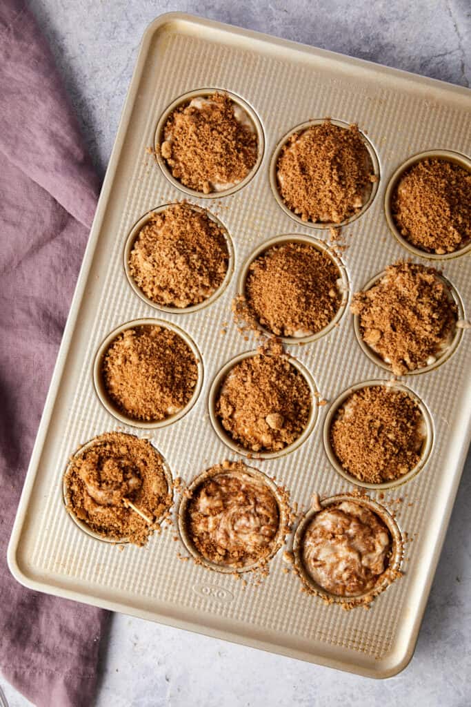 Overhead view of cinnamon swirl banana muffins with the brown sugar topping and a toothpick is swirling the topping.