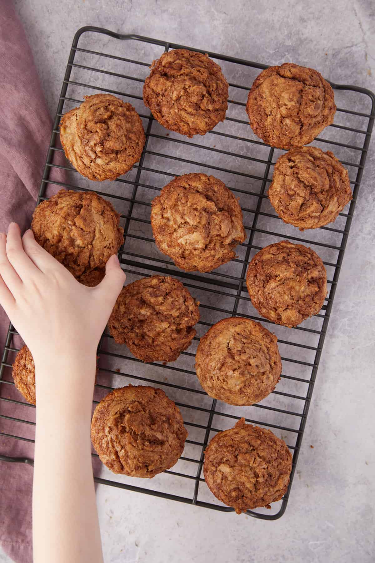 Overhead view of muffins with a kids hand grabbing one of the muffins.