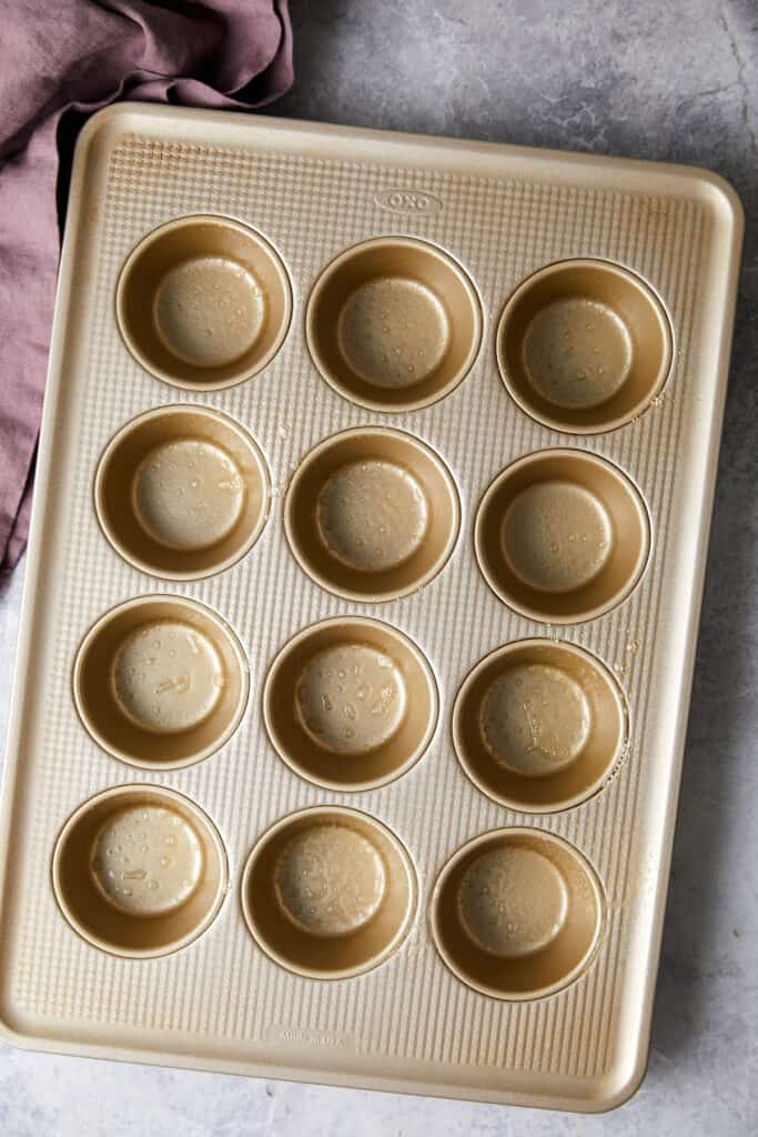 overhead view of muffin tin sprayed with cooking spray. 