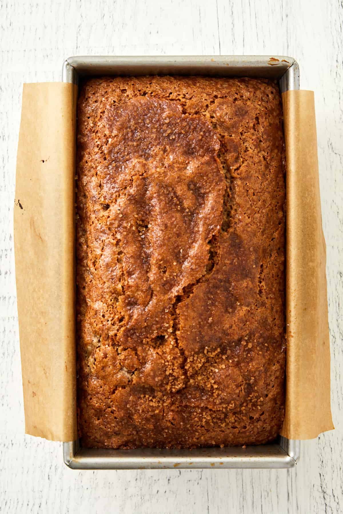 Overhead view of rhubarb banana bread baked in loaf pan lined with parchment paper.