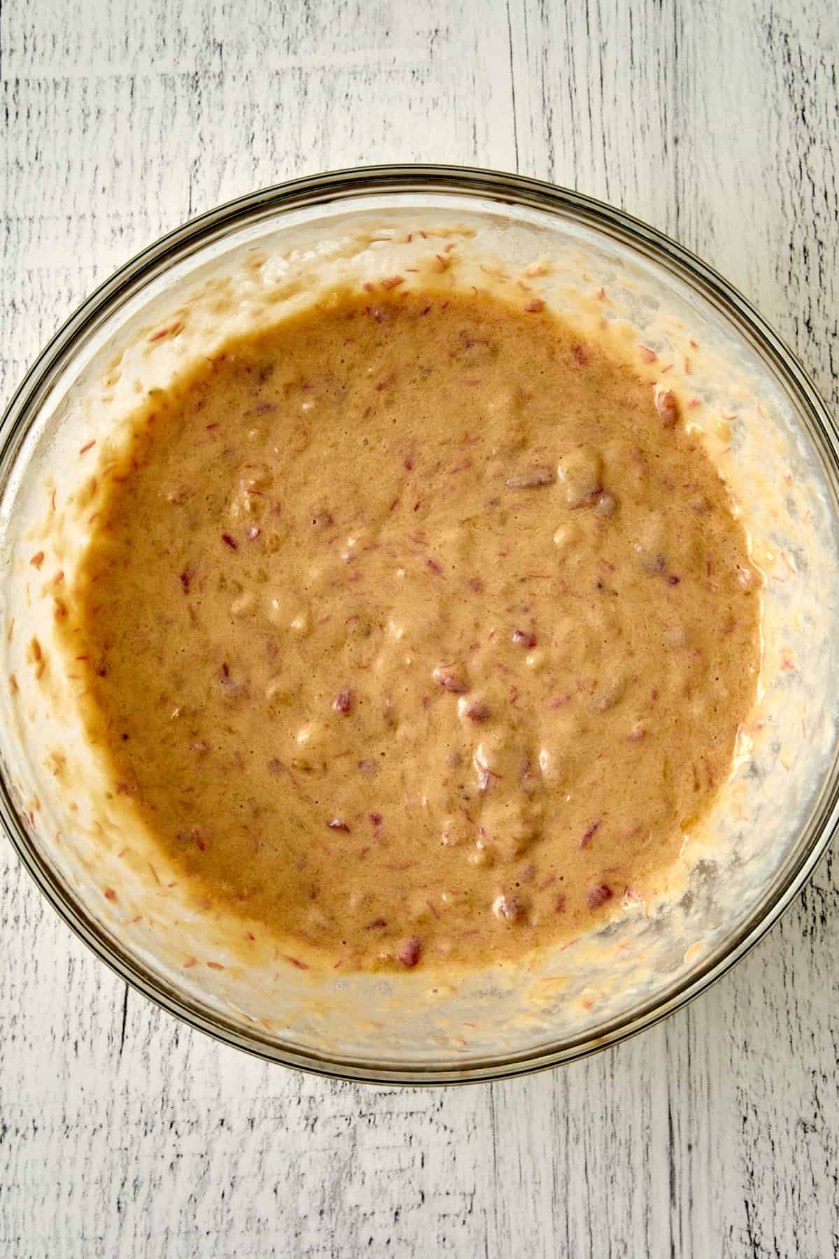 Overhead view of wet ingredients mixed together in a glass mixing bowl.