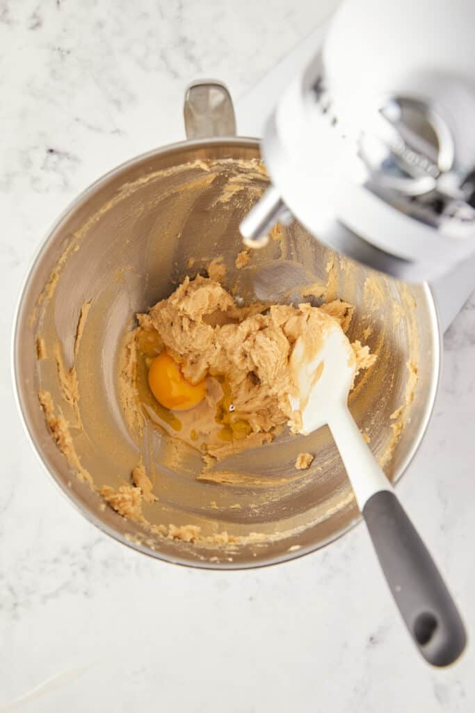 overhead view of butter, brown sugar and a raw egg in the mixer bowl.