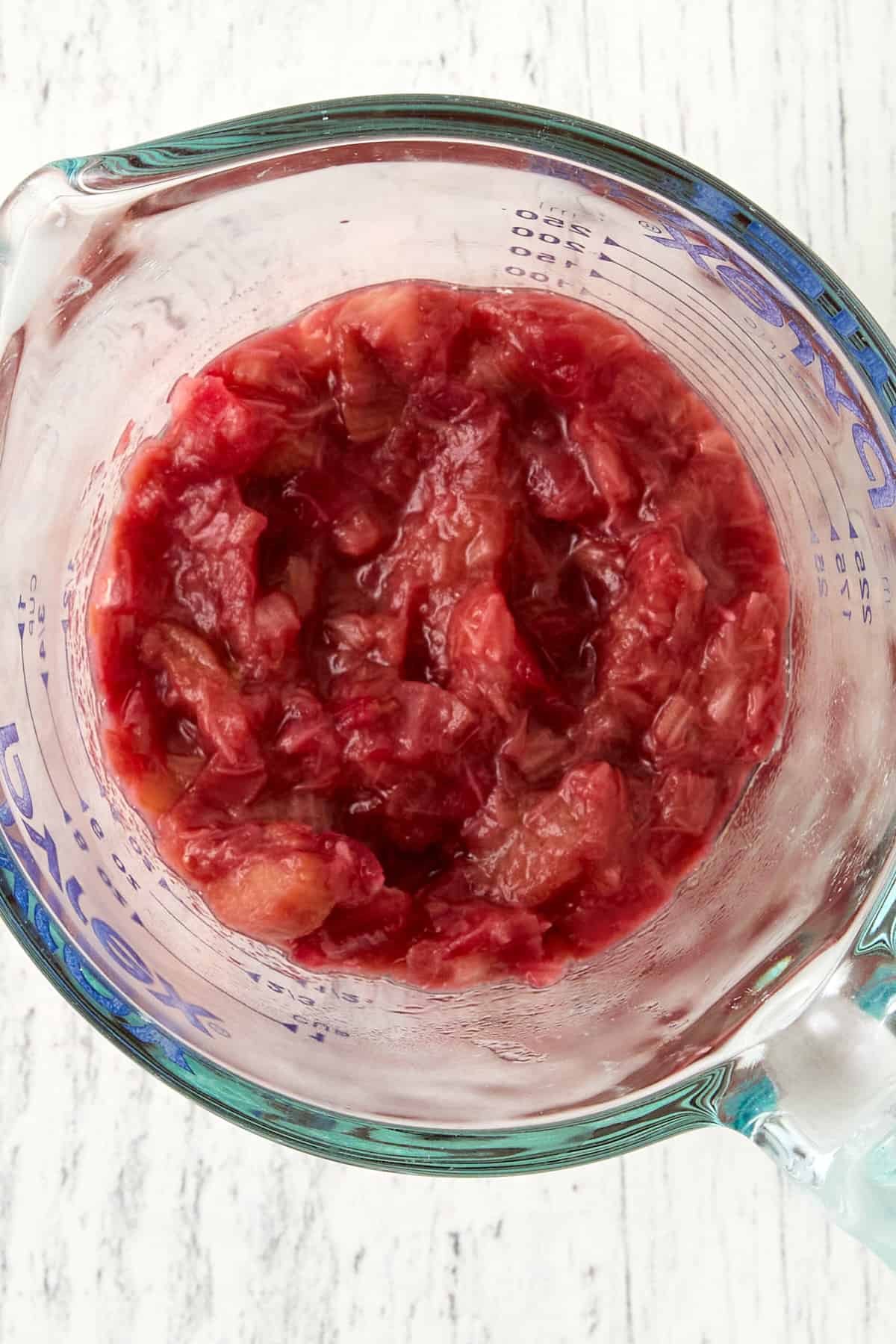 Overhead close-up picture of cooked-down rhubarb in glass measuring cup.