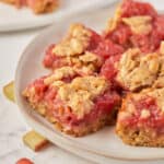 Close up view of rhubarb oatmeal bars on a white plate.