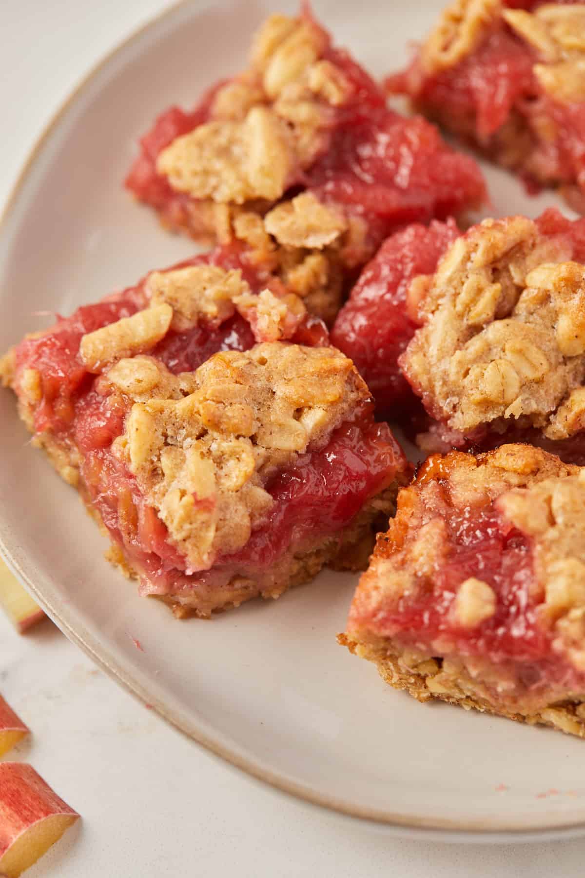close up view of baked rhubarb bars on a white plate.