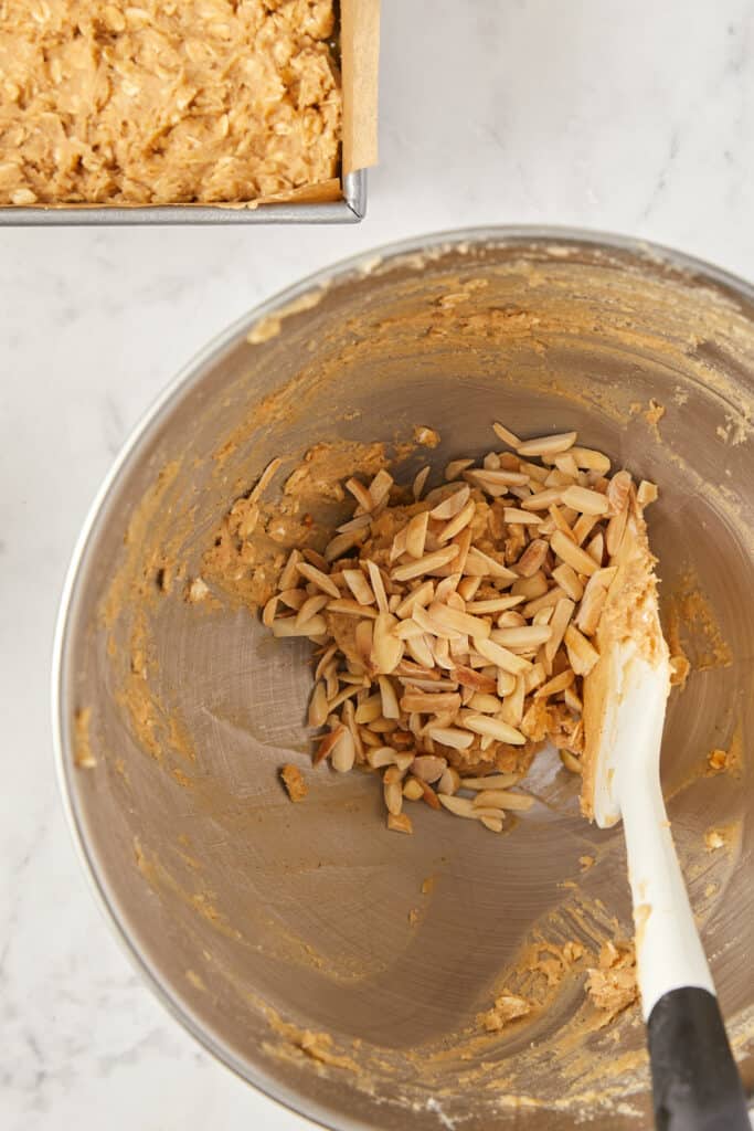 rhubarb oatmeal bars batter in mixing bowl with sliced almonds added.