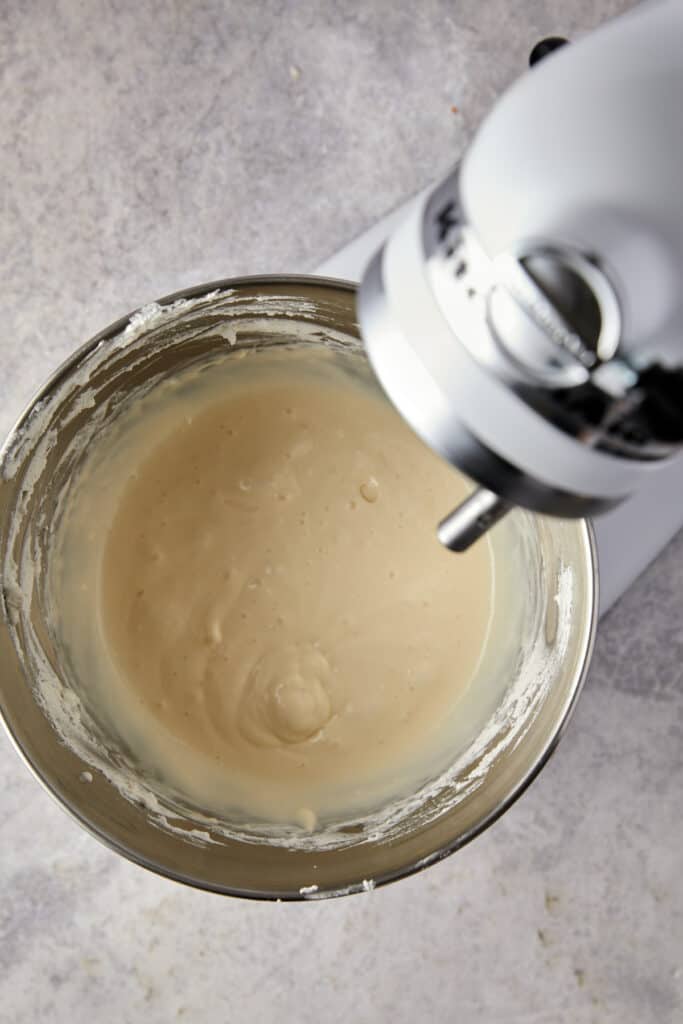 Overhead view of cream cheese and condensed milk mixed in a mixing bowl.