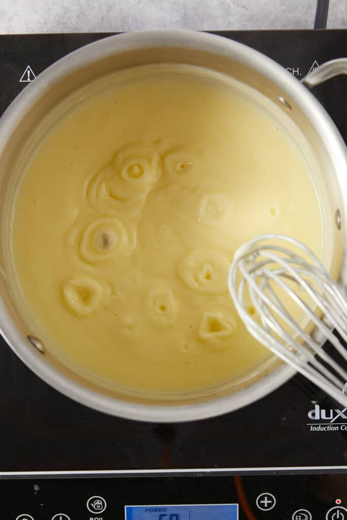 Overhead view of bubbling pudding in a stainless steel pot.