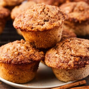 close up view of 3 baked cinnamon banana muffins on a white plate.